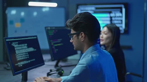 Software engineer coding on computer monitor in high-tech office