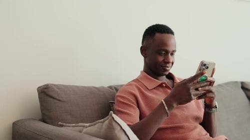 Man Relaxing on Couch Using Mobile Phone