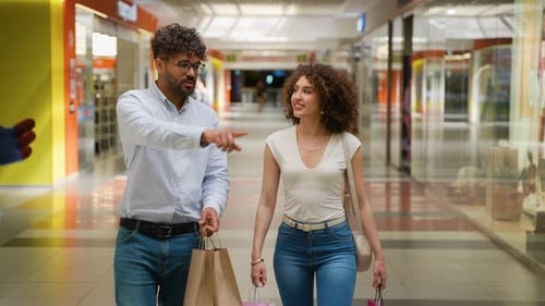 Couple Walking and Pointing at Storefront in Shopping Mall