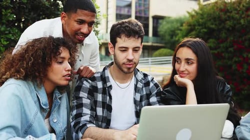 Young Adults Gather Around Laptop, Smiling Together