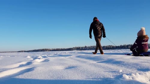 Family walk on snow with sled and pram. Low angle