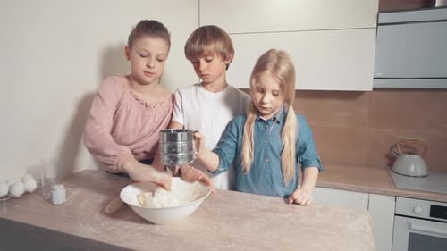 Drei schöne Kinder Hilfe in der Küche und mischen den Teig auf einem weißen Teller