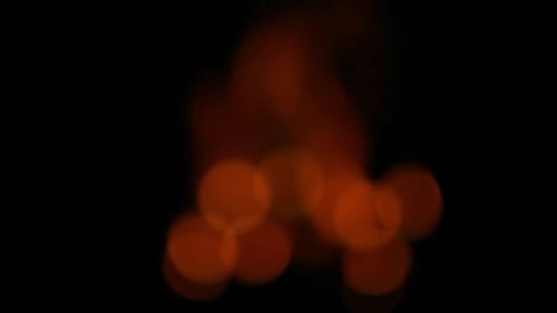 Bokeh lights created from a burning campfire, slow zoom out to fire burning.