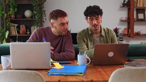 Deux collègues masculins collaborent sur un projet avec des ordinateurs portables au bureau à domicile