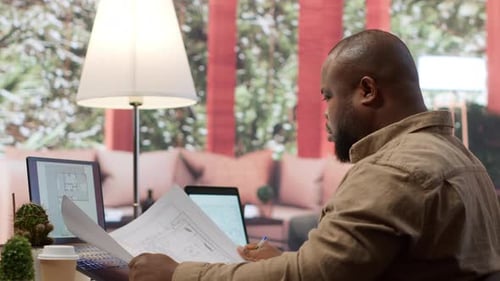 Businessman Analyzing Architecture Blueprints for New Office Space Layout