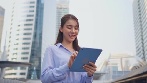 Asian young businesswoman using digital tablet while standing in the city.