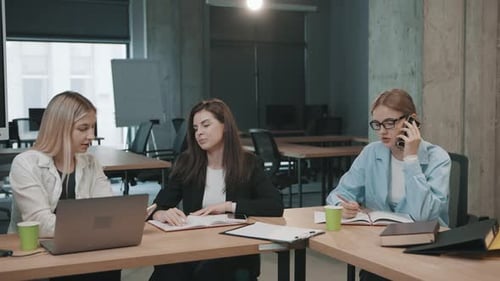 Les collègues discutent de projets au bureau tout en utilisant des ordinateurs portables et en prenant des notes lors d'un atelier partagé