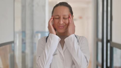 Portrait of Mixed Race Female Doctor with Headache in Office