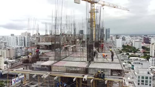 Luftflug mit 180-Grad-Drehung zur Erfassung von Arbeitern bei der Arbeit an einem Immobilienprojekt, mit Hintergrund von