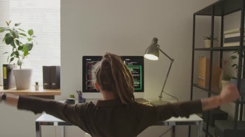 Back View of Female Programmer Stretching at Workplace