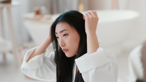 Woman Examining Hair in Bright Bathroom