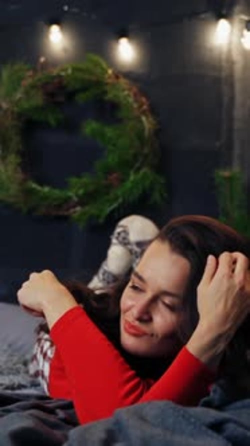 Woman Smiles Lying on Bed with Christmas Wreath