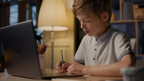 Boy Studying at Desk with Laptop at Night