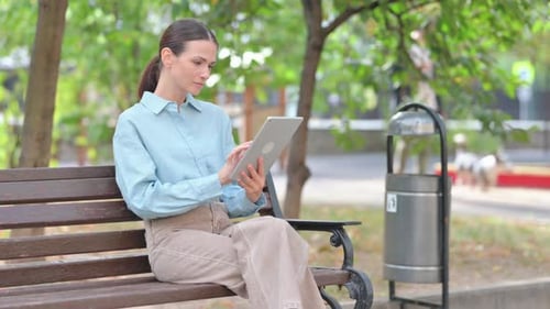 Woman Using Tablet on Park Bench, Daytime