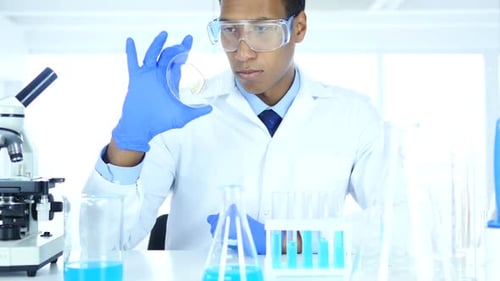 Scientist in Laboratory Studying Reaction in Watch Glass