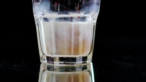 Closeup Glass Bottom with Black Coffee Pouring in White Milk in Slow Motion Extreme Closeup Mixing