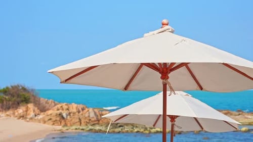 Close up of beach parasols, umbrella sunshades and tropical sea on summer breeze