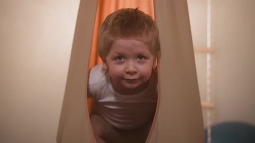 Young Boy Smiling Inside Fabric Pod at Home