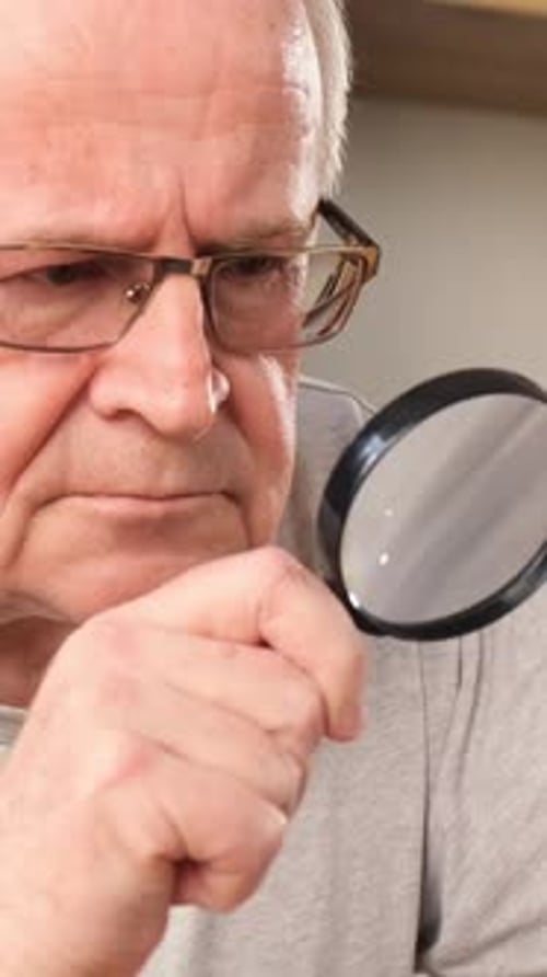 Senior Adult Looking Through Magnifying Glass