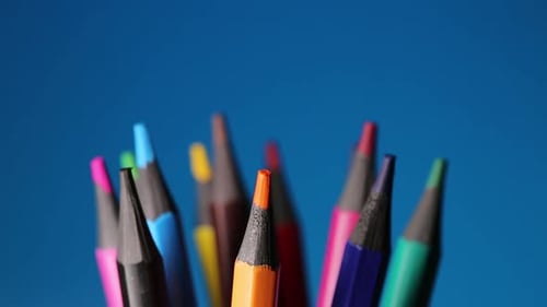 Colored Pencils Rotate On A Blue Background, Stationery For School