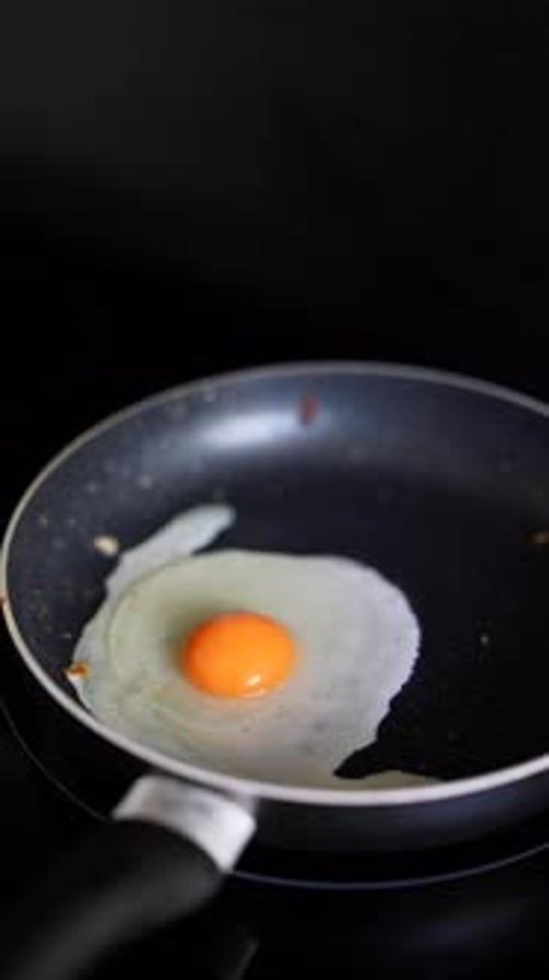 A Single Egg is Frying in a Pan on a Dark Background Creating a Simple and Appetizing Scene
