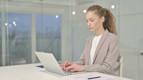 Business Woman Smiling and Typing on Laptop in Office