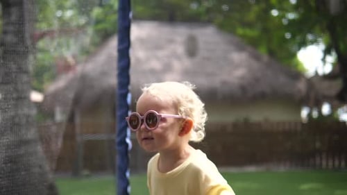 Cute Child Jumping on Trampoline in Tropical Garden