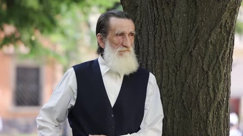 Elderly Man Walking Slowly Through the City Streets on a Sunny Day