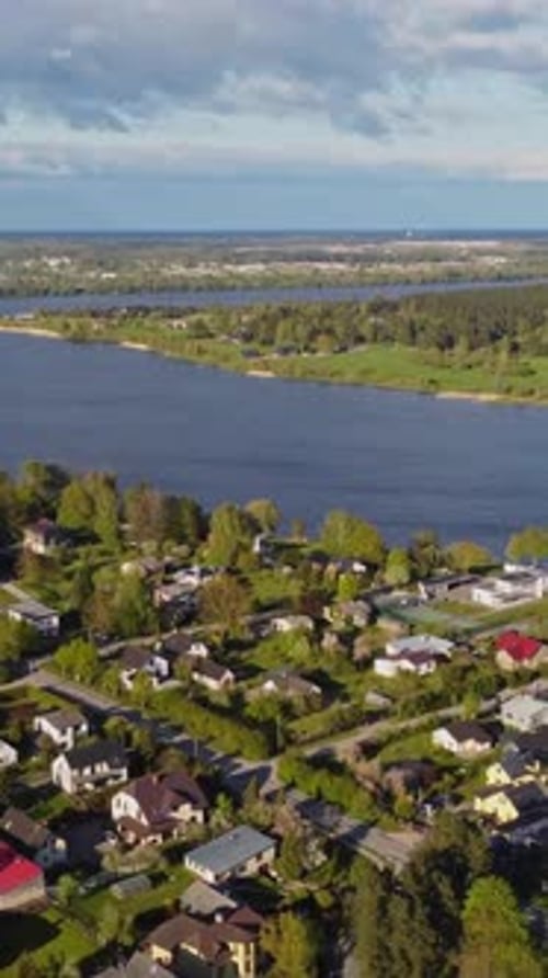 Slow drone flyover showing Katlakalns residential area along Daugava River, Gulf of Riga beyond