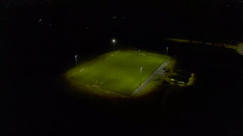 Smooth drone approach toward football practice match at night time.