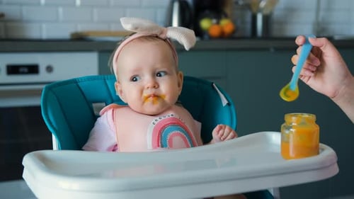 Baby Girl Eating Food in High Chair
