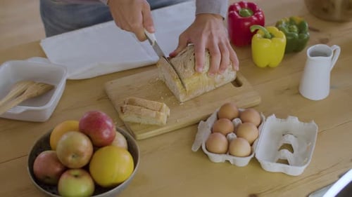 Adult Cutting Bread in Bright Kitchen