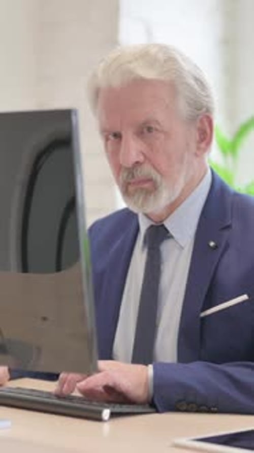 Senior Man Working on Computer in Office Setting