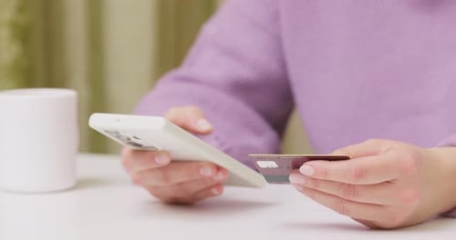 Woman Using Phone and Credit Card Indoors