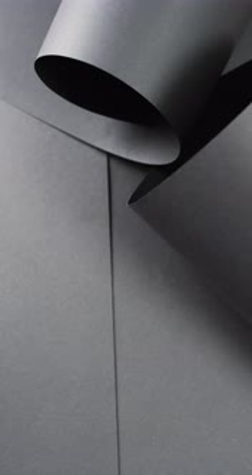 Vertical video of close up of rolled up black paper and copy space on black background