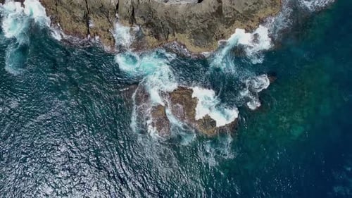 Drone aerial panning view of waves breaking on a rocky coastline