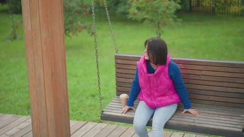 Female Relaxing on Garden Swing Woman Resting Peacefully on Outdoor Swing Serene Scene of Woman