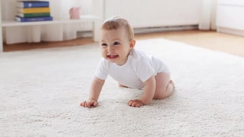 Fröhliches kleines Baby, das zu Hause auf dem Teppich krabbelt und das Wohnzimmer erkundet