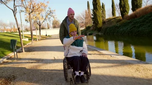 Young Man Pushing Senior Woman in Wheelchair in the Park