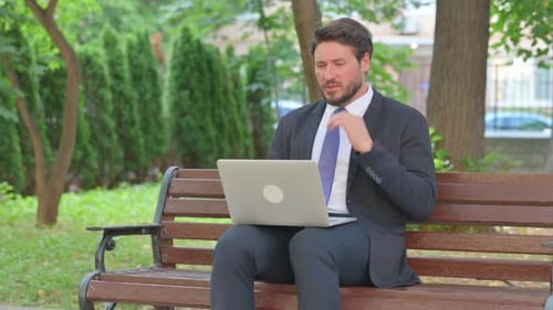 Man in Suit Working on Laptop Outdoors
