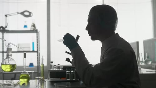 A Scientist in a Research Laboratory Examines a Sample on a Micropreparation Using a Microscope The