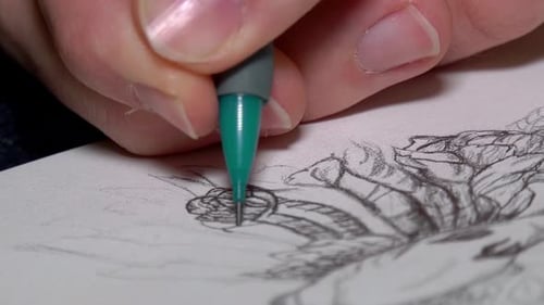 Person sketching with a green pencil on a white paper. CLose up shot
