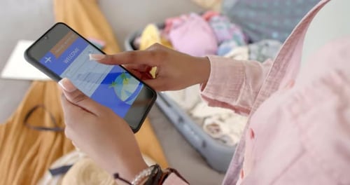 A young African American woman is browsing a travel booking app on a smartphone