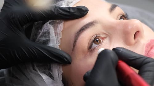 Cosmetologist Applying Permanent Make Up on Eyes Closeup
