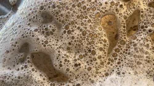 Reinigungsschaum läuft auf dem Eisenstück herunter