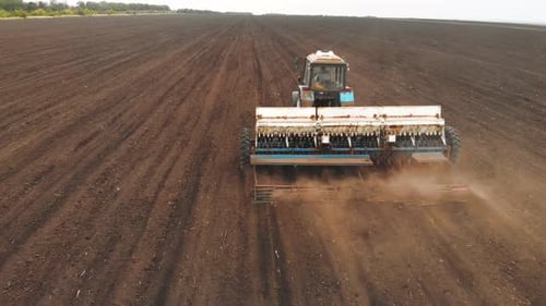 Drone Sliding Shot of a Farmer in Tractor Seeding on Sunny Day Footage of Sowing Agricultural Crops