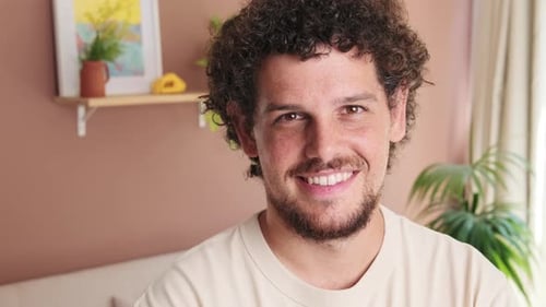 Close-up of guy standing in cozy living room looking at the camera with smile
