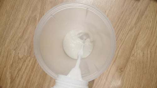 Pouring White Liquid Into A Clear Container