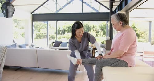 Physical Therapist Assists Senior Woman with Leg Exercises