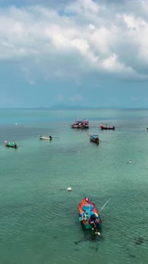 Des bateaux de pêche se sont rassemblés dans des eaux calmes près d'un village côtier en plein jour